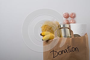 Volunteer with donation box with foodstuffs. Male hands hold a set of food products in a paper bag