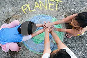 Volunteer family paints a beautiful world with the message Planet on asphalt and put hands together. Concepts of world environment