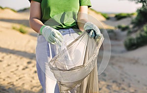 Volunteer female collect trash, plastic garbage bottles on the beach. Ecology, environment, pollution and ecological problems