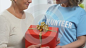 Volunteer giving birthday gift to pensioner, charity concept, financial support