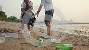 Volunteer happy family kids picking plastic bottle into trash plastic bag black for cleaning beach