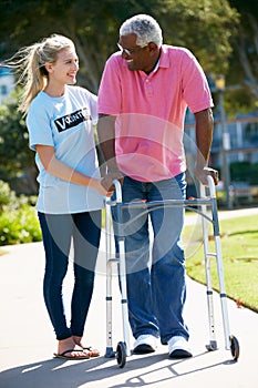 Volunteer Helping Senior Man With Walking Frame