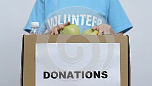 Volunteer packing food in cardboard box, gathering donations for nursing home