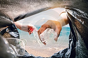 The volunteer picking up a bottle plastic in to a bin bag and the sea background