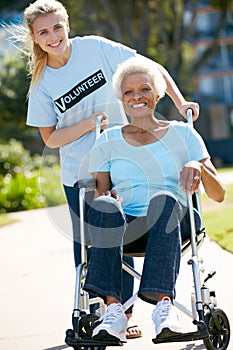 Volunteer Pushing Senior Woman In Wheelchair