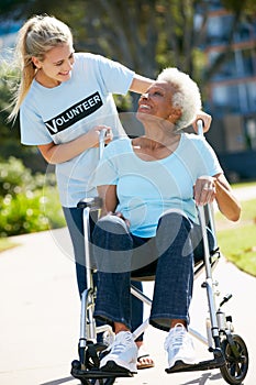 Volunteer Pushing Senior Woman In Wheelchair