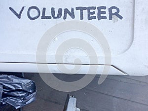 Volunteer sign handwritten on white plastic tub lid