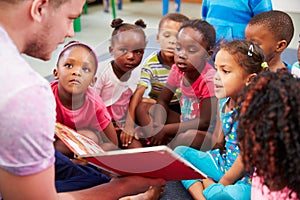 Volunteer teacher reading to a class of preschool kids photo