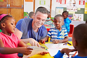 Volunteer teacher sitting with preschool kids in a classroom photo