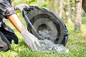 volunteer team picking up plastic bottles, putting garbage in black garbage bags to clean up at parks,