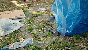 Volunteer using tongs tool to collect trash and plastic waste from the woods