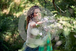 Volunteer woman picking up trash in nature. Cleaning up forest or park doing charity work. Environmentalism, green, lifestyle