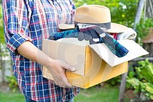 Volunteer woman provide clothing donation box with used clothes and doll to support help for refugee, homeless or poor people in