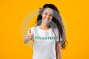 Volunteer Woman Showing Like Gesturing Thumbs-Up Standing On Yellow Background