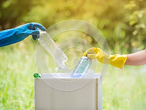 Volunteer women collect plastic water bottles in the park area, From people who refuse to throw in the trash into paper box for