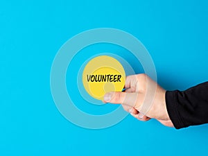 Volunteering concept. Help, assistance, charity and support community. Male hand holding a yellow circle sign with the word