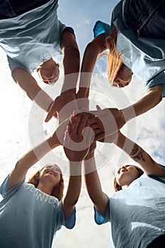 Volunteering. Young people volunteers outdoors standing hands together close-up bottom view smiling excited