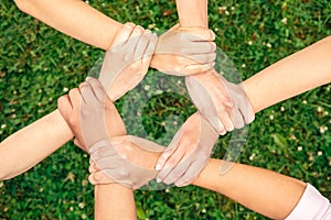 Volunteering. Young people volunteers outdoors together holding hands unity top view close-up