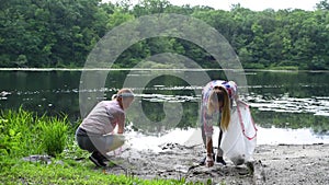 Volunteers cleaning garbage near river. Women picking up a bottle plastic in the lake. Environmental pollution