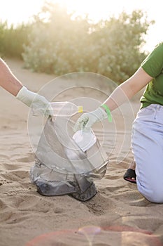 Volunteers collect trash, plastic garbage bottles on the beach. Ecology, environment, pollution and ecological problems concept