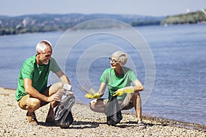 Volunteers gathering garbage on river bank. Ecology concept