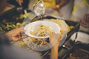 Volunteers hand over delicious food to homeless people who are starving and need food : concept of free charity food