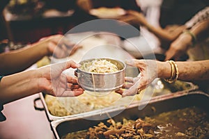 Volunteers hand over delicious food to homeless people who are starving and need food : concept of free charity food