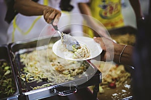 Volunteers hand over delicious food to homeless people who are starving and need food : concept of free charity food