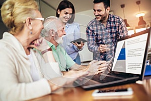 Volunteers help senior people on the computer. Young people giving senior people introduction to internet