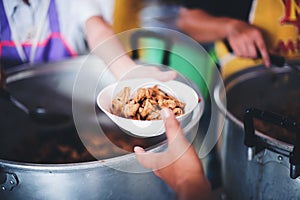 Volunteers help to draw food for the poor who are waiting to receive food in hunger