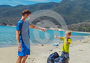 Volunteers paradise beach sand lazur sea. Man, boy pick up garbage into black bag. Son refuse to wear blue face mask