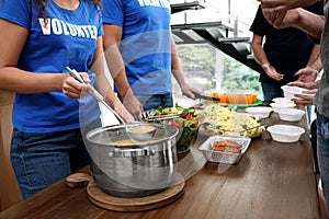 Volunteers serving food to  people in charity centre, closeup