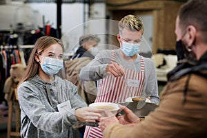 Volunteers serving hot soup for homeless in community charity donation center, coronavirus concept.