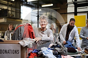 Volunteers sorting out donated clothes in community charity donation center.