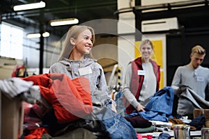 Volunteers sorting out donated clothes in community charity donation center.