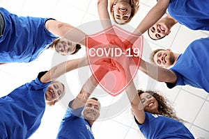 Volunteers uniting to help during COVID-19 outbreak. Group of people holding hands together on background, shield