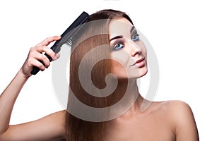 Voluptuous girl with blue eyes combing her perfect healthy streight brown hair with comb on white background