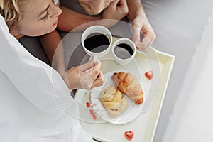 Voluptuous loving couple drinking coffee in bed