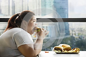 Voracious fat woman eating burger in the restaurant