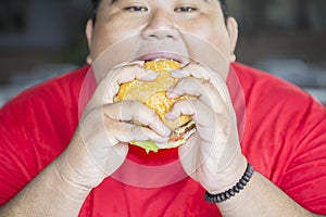 Voracious obese man enjoying a big hamburger