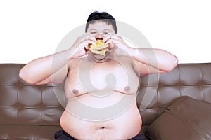 Voracious obese man with hamburger on studio