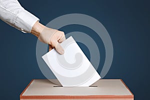 Voter Holds Envelope In Hand Above Vote Ballot. Blue background. Democracy Concept