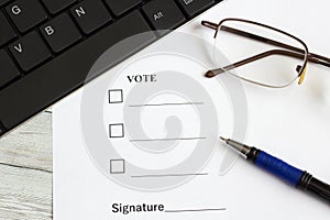 The voting form on the office table near the keyboard, pen and glasses