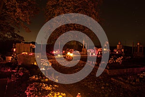 Votive candles lantern burning on the graves in Slovak cemetery at night time. All Saints' Day. Solemnity of All Saints