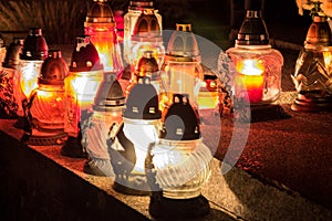 Votive candles lantern burning on the graves in Slovak cemetery at night time. All Saints' Day. Solemnity of All Saints