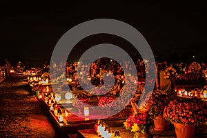 Votive candles lantern burning on the graves in Slovak cemetery at night time. All Saints' Day. Solemnity of All Saints