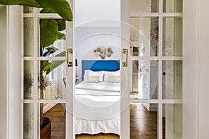 Voyeur view of a decorated bedroom through sliding wooden doors and mirror