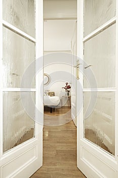 Voyeur view between wooden and glass doors to a bedroom