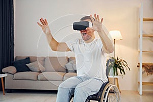 In VR glasses. Disabled man in wheelchair is at home