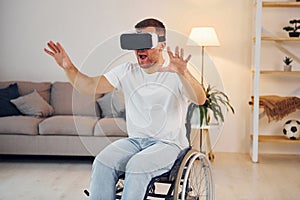 In VR glasses. Disabled man in wheelchair is at home